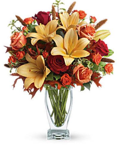 <p>Roses, lilies and oak leaves create a fantasy of fall flowers. Send this tall, elegant arrangement to wish someone a happy autumn or joyous Thanksgiving. The warm color palette and Couture Vase make a stylish seasonal statement.<br />
Orange, dark orange and red roses blend with orange asiatic lilies, green salal and pitta negra. Subtle seasonal elements include dried oak leaves and millet.</p>